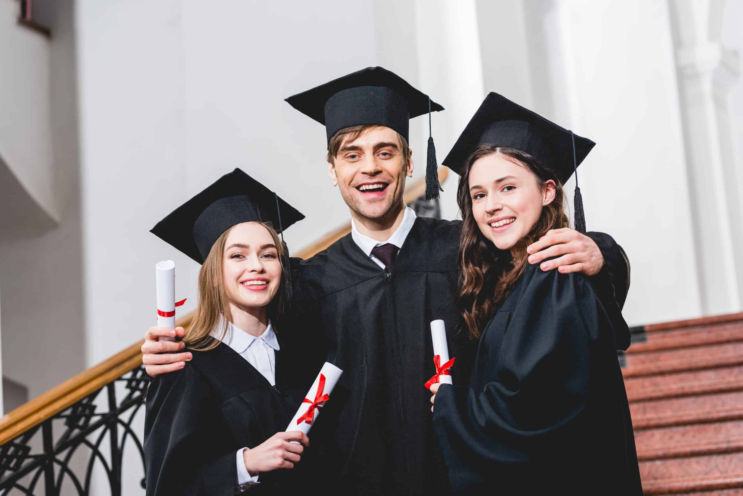 cheerful man in graduation cap hugging attractive girls while holding diploma cheerful man in graduation cap hugging attractive girls while holding diploma