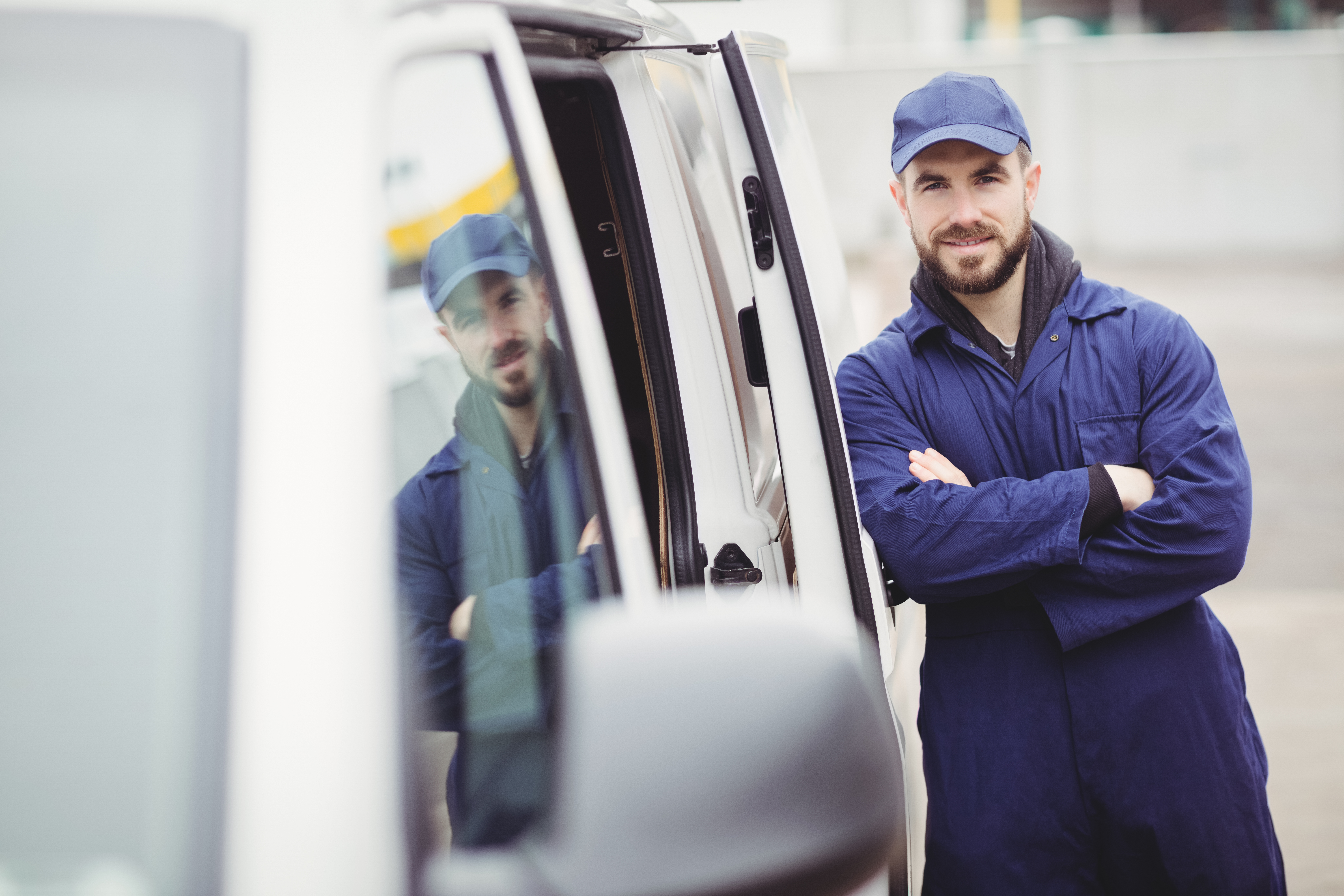 Repairman with arms crossed leaning against his van
