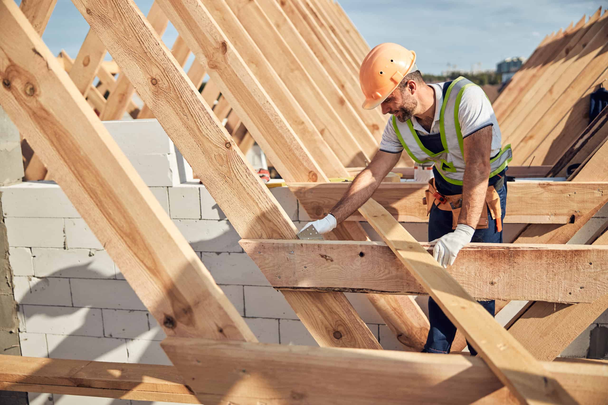 Professional builder in protective equipment building a roof Professional builder in protective equipment building a roof