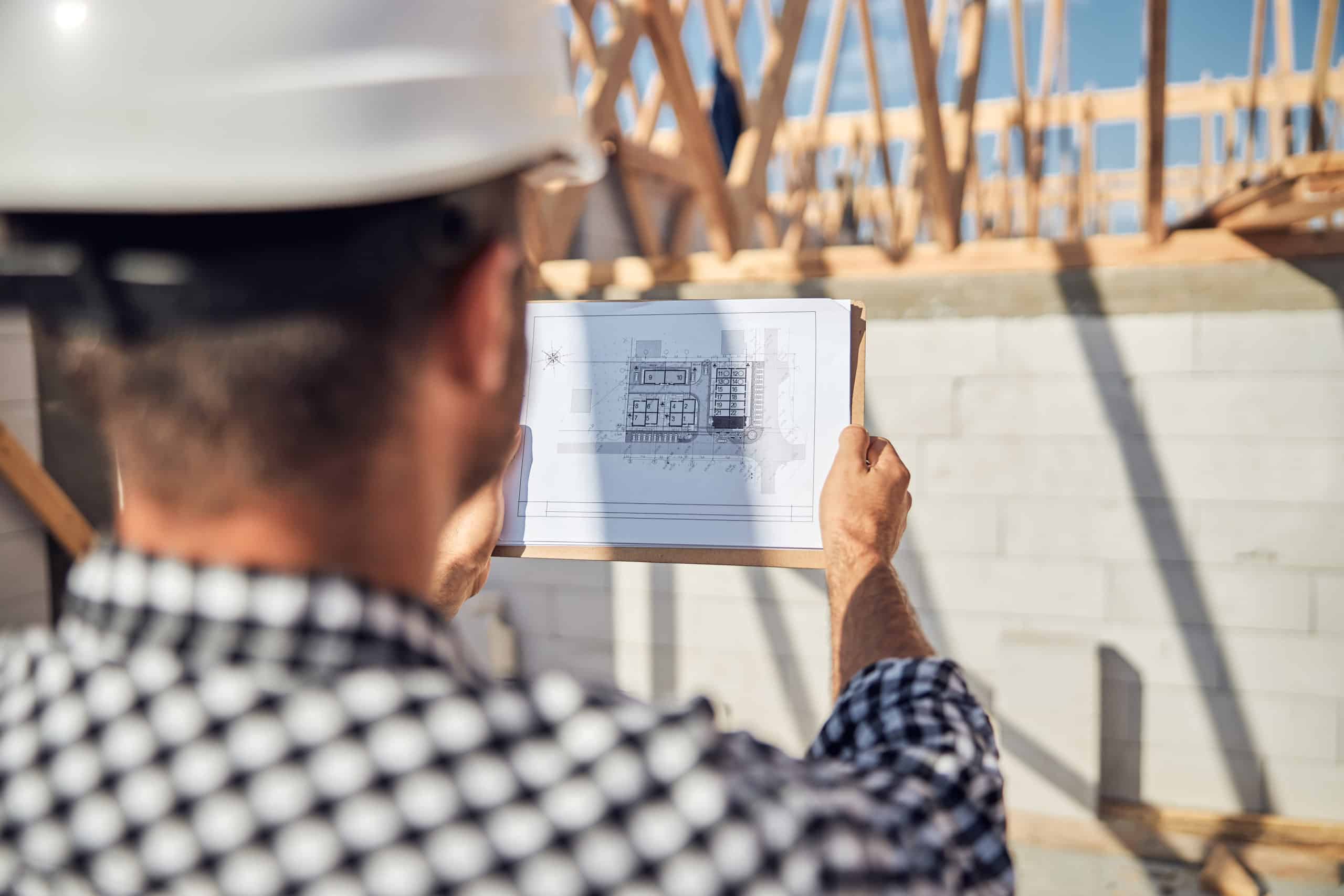 Qualified construction supervisor checking building whiteprints at construction site Qualified construction supervisor checking building whiteprints at construction site