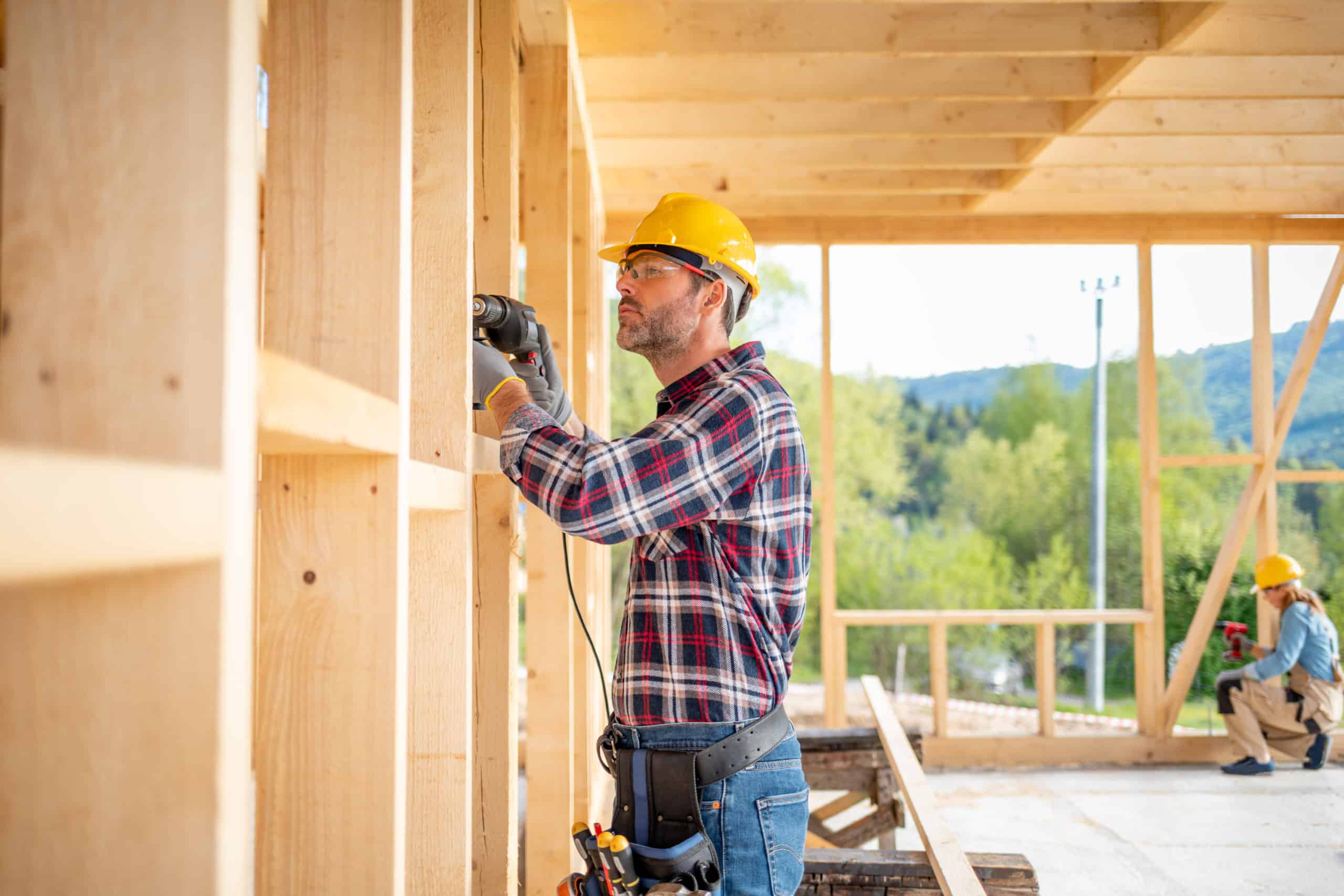 Worker using drill working on construction of wood frame house Worker using drill working on construction of wood frame house